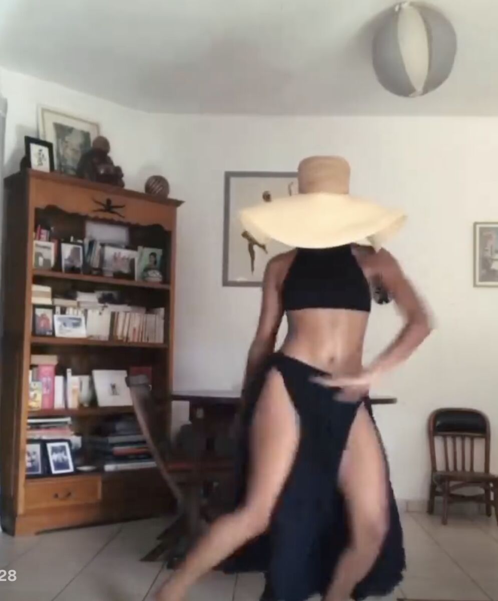 Woman dancing in her living room with a wide-brim hat